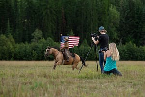 Boy riding with American Flag with two photographers taking photos