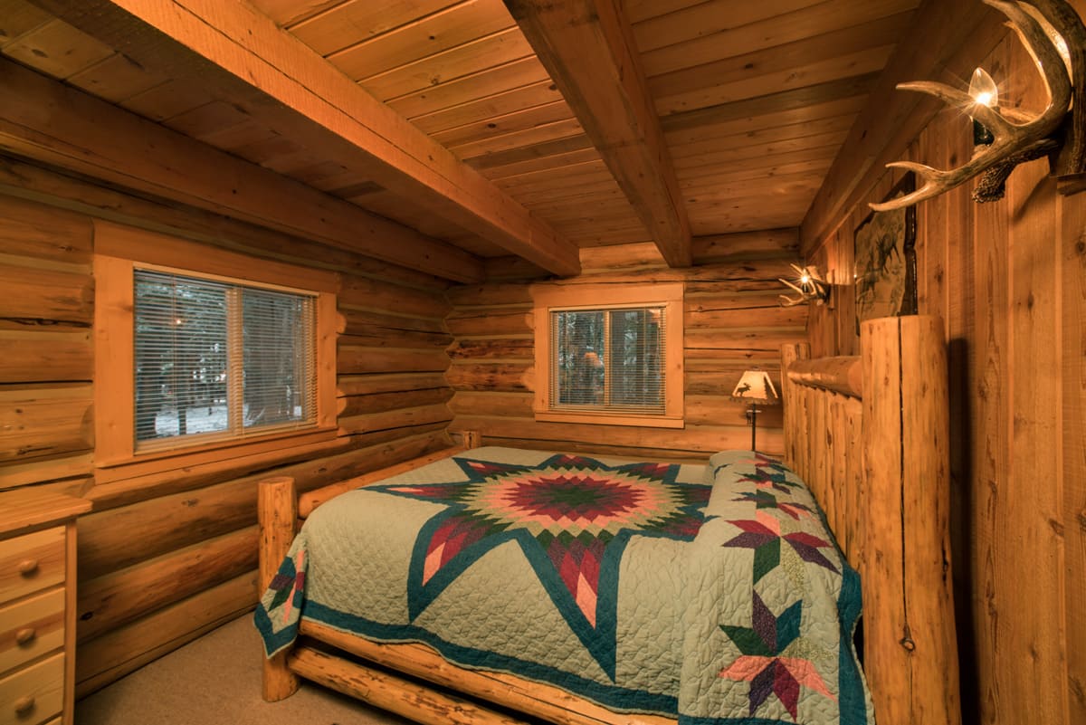 Western Pleasure Guest Ranch rustic cabin bedroom with log bed and teal quilt