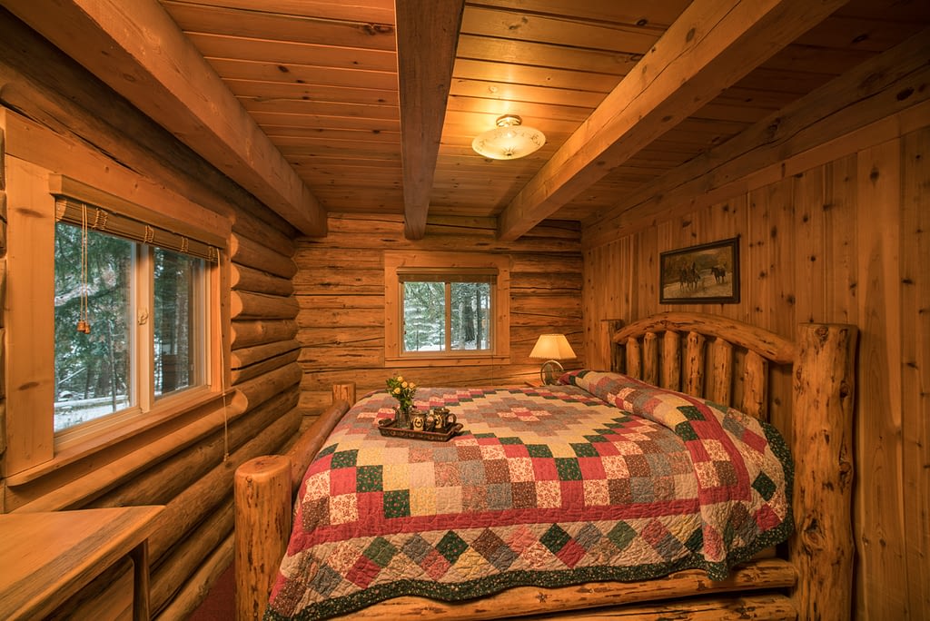 Pacific Northwest cabin rental private bedroom log walls and log bed with quilt