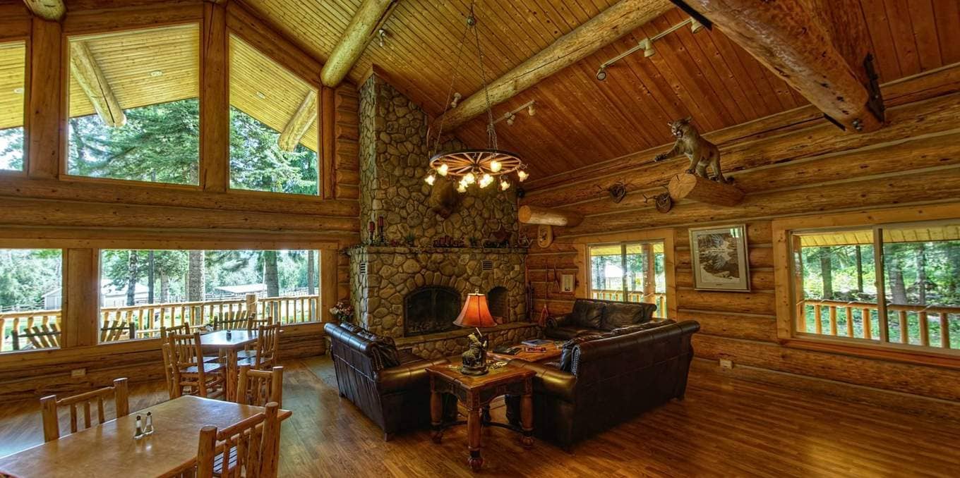 Great room in the log lodge at Western Pleasure Guest Ranch with leather couches and river rock fireplace