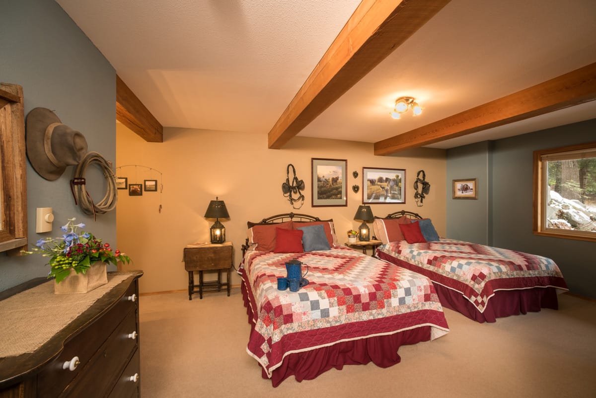 Guest room with two double beds with quilts antique decorations on the walls