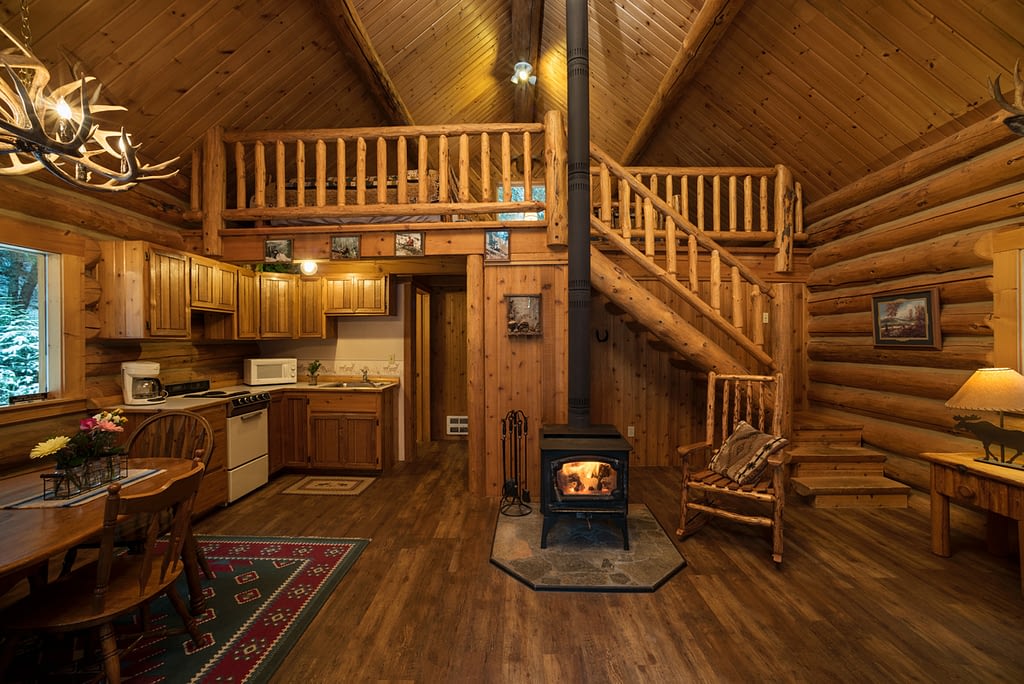 Western Pleasure Guest Ranch Hunter Cabin interior photo with wood fire burning, log railings and wood floor