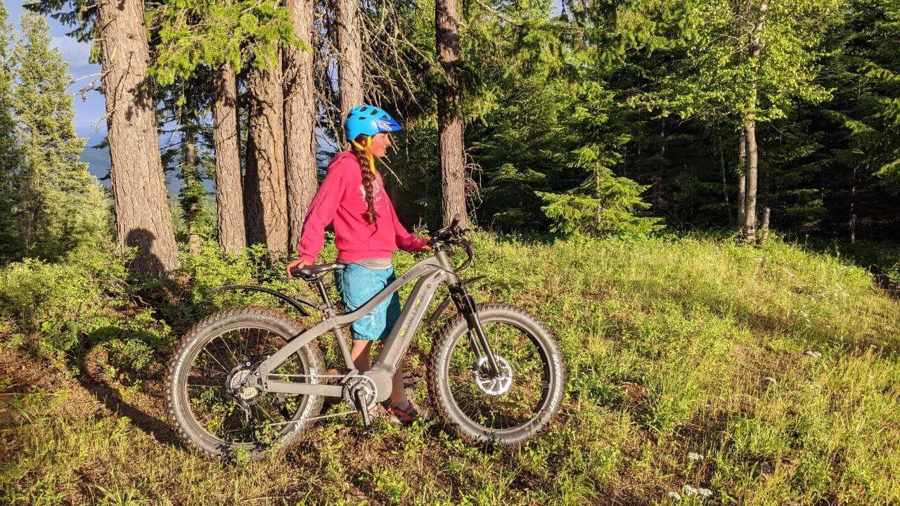 A woman stands next to a Quietkat eBike while taking a rest on a mountain ride