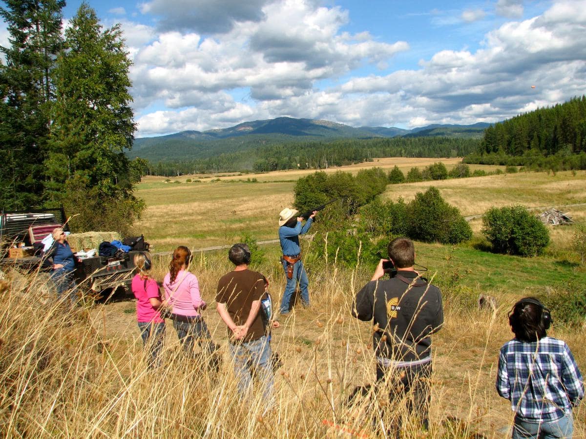 a crowd watches a cowboy shooting Shooting Clay Pigeons
