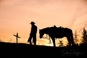 Silhouette of cowboy and horse at cross