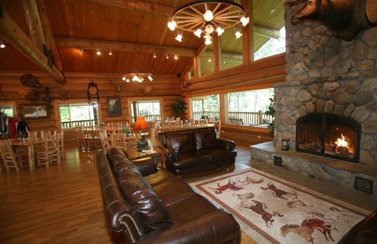 Lodge great room with warm fire burning in river rock fire place